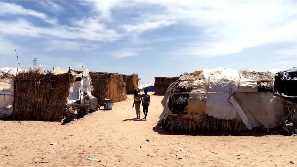 Two children walking in Goz Al Salam displacement camp in White Nile State, Sudan.